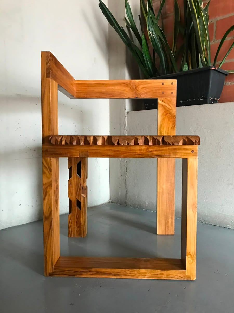 Vista lateral de una silla de madera de Co-Creator con asiento tallado