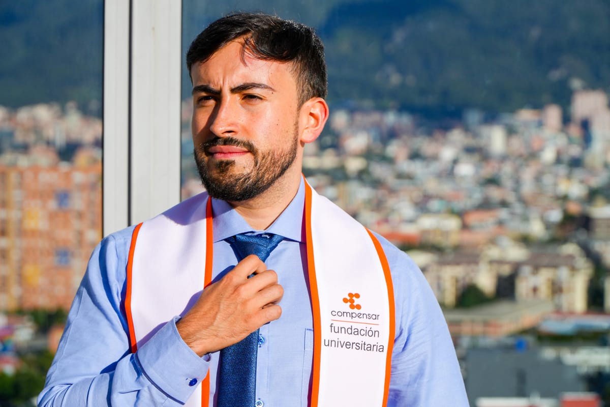Gabo ajustándose la corbata con la banda de graduación, mirando a un lado, con luz cálida de tarde