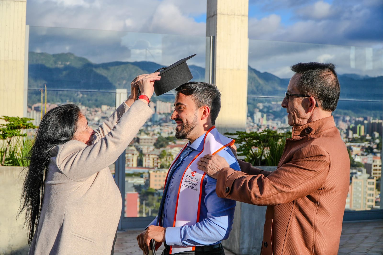 La mamá de Gabo ajusta el birrete sobre su cabeza mientras su papá le pone la mano en el hombro, en una terraza de Bogotá